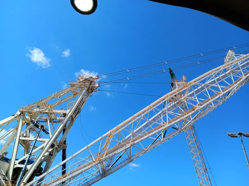 Looking up at the boom and mast against blue sky