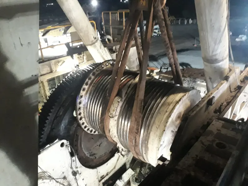 Hoist drum lifted in slings beside its gear at night