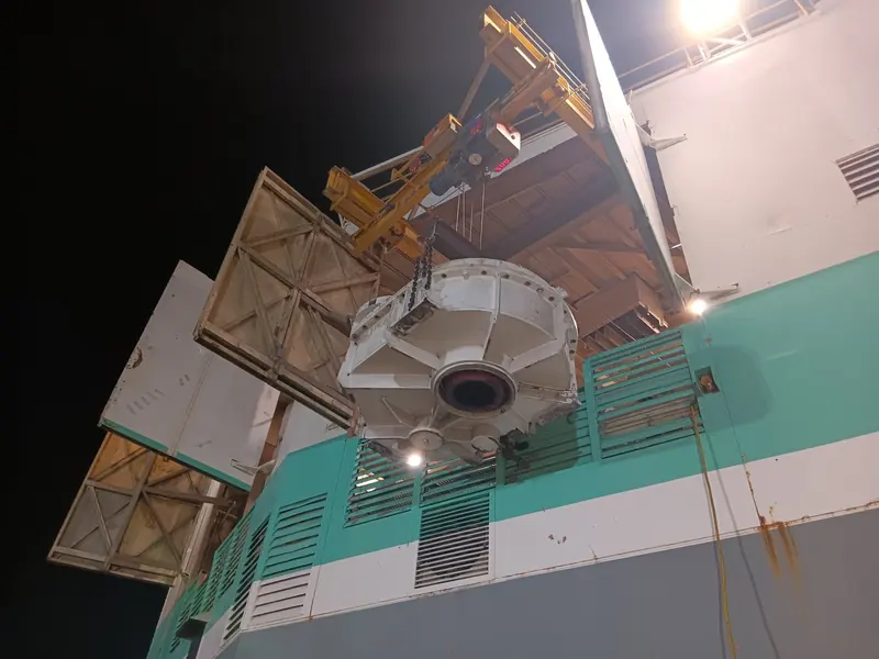Gear case lifted out of a dragline house by the deck crane at night