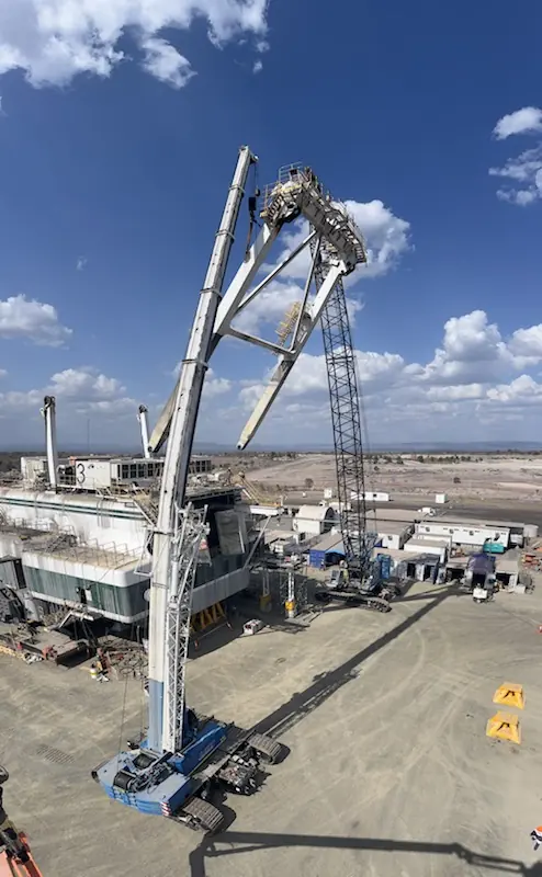 Aerial view of a dragline mast being lifted by crawler cranes